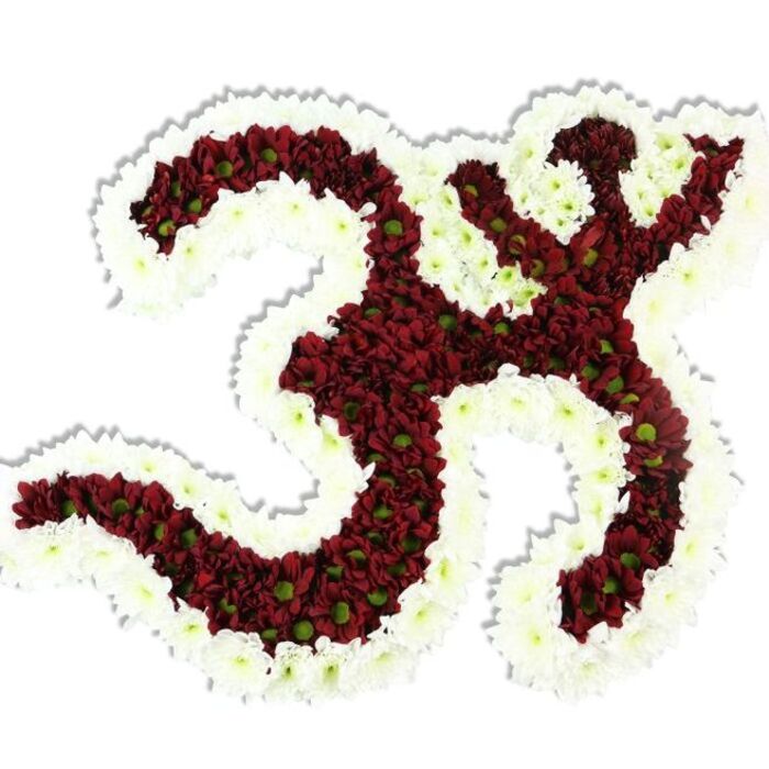 Here the sacred Om is translated into floristry with exacting care: the emblem is sculpted from a dense sea of small, dark red to maroon chrysanthemum-like flowers, their tight heads forming the familiar threefold curve, the descending stroke, and the delicate crescent with its point. Each red blossom shows a small lime-green center, an almost jewel-like detail that adds depth and organic variation across the mass of colour. Surrounding and sculpting the symbol is a continuous ribbon of immaculate white spray chrysanthemums; this thick white border outlines the form, frames the inner negative spaces, and heightens the symbol's graphic clarity against the plain white background. The composition sits slightly above the backdrop, a soft shadow revealing its three-dimensional construction and the meticulous placement of each bloom. Tactile cues come through the description - the petals appear cool, silky, and closely woven - while the overall impression remains one of reverence, serenity, and quiet strength. In a Bexleyheath context this piece reads as a considered tribute for religious ceremonies, remembrance services held near the Broadway shopping precinct, or special occasions at local cultural centres. The arrangement conveys devotional intent as much as botanical skill, the interplay of maroon, lime, and snow-white petals translating centuries-old symbolism into a contemporary floral vocabulary of comfort and honour.